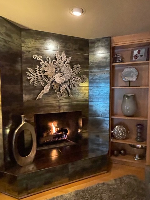 lit fireplace with marble looking stone and wood accents
